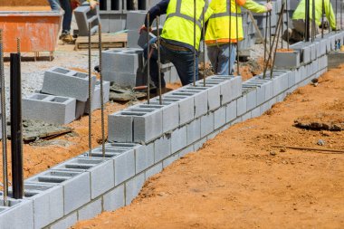 Duvarcı duvar ustası bir şirket inşaat projesinin bir parçası olan beton blokları inşa ediyor.