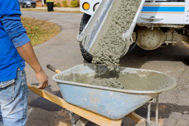 Karıştırıcı kamyon inşaat alanındaki el arabasına beton döküyor.