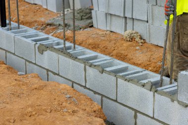 Mason tuğla ustası inşaat için havalanan beton bloklardan duvar örüyor.