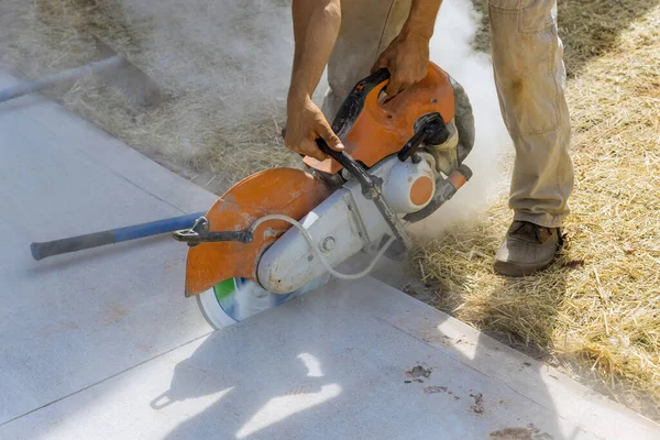 Construction worker cutting concrete sidewalk using diamond blade saw machine