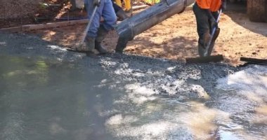 İnşaat müteahhitleri beton inşaat projesinde çalışırken garaj yolunu dökerken ıslak beton döküyorlar.