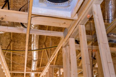 Tavan arasında ahşap kirişlerin arasında havalandırma boruları döşenen yeni bir bina inşa ediliyor.