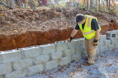 Yapılan yeni mülkte beton blok istinat duvarı inşa edilirken insan seviyeleri aracı