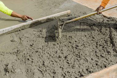 İşçiler yeni bir kaldırım oluşturmak için evin yan tarafına çimento döküyorlar.