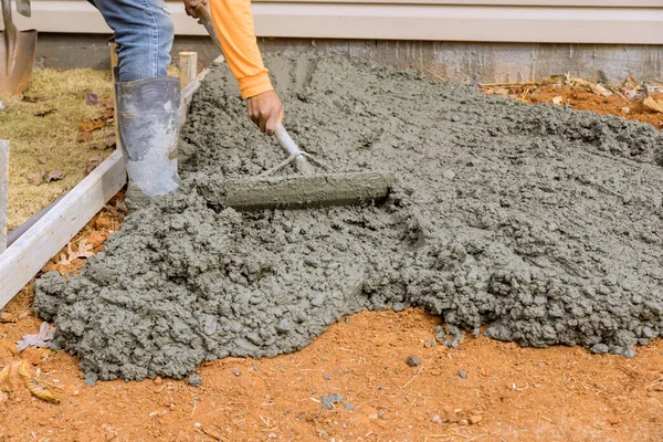 stock image On side of house, construction workers pour cement to create an additional sidewalk as part renovation project