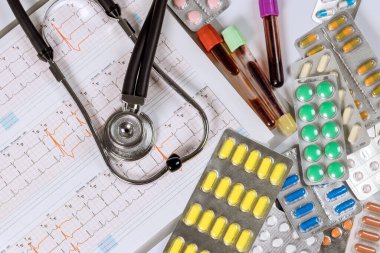 Ofisteki kardiyo doktorunda kardiyogram da dahil olmak üzere çeşitli ilaç kabarcıkları ve stetoskop var.