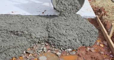 Karıştırıcı kamyon inşaat alanındaki el arabasına beton döküyor.