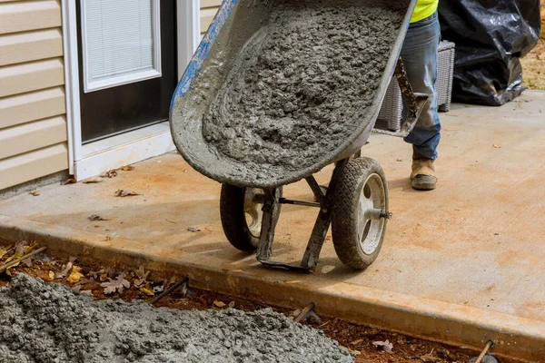 ホイールバローを使用して作業者とコンクリート打設湿式セメントで家の近くに新しいコンクリート歩道を作る — ストック写真