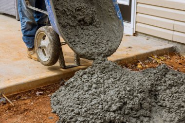 El arabası yardımıyla, evin yakınına ıslak beton dökerek yeni beton patikalar yapıyorlar.