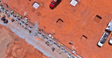 İnşaat alanı, iskeleye beton bloklar döşeyen işçiler tarafından işleniyor.