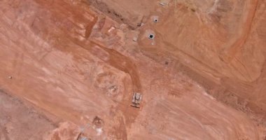 Toprak hareket eden makinelerin, ağır makinelerin ve traktörlerin aynı anda çalıştığı büyük inşaat alanının havadan görüntüsü.