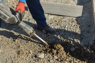 Yolun beton yüzeyi, matkap kullanarak inşaat işçileri tarafından kazılıp delinmiş.