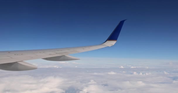 在毛茸茸的云天的背景下 可以看到一个飞机机翼在云层上方从窗户飞出 — 图库视频影像