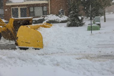 Snow blizzard clean up of snow with tractor during huge snowstorm in winter time clipart