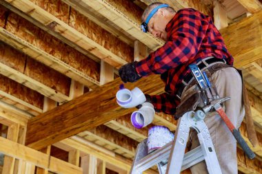 Tesisatçı, konutlardaki plastik boruları birleştirmek amacıyla plastik tutkalla PVC plastik boru yapıştırıyor.