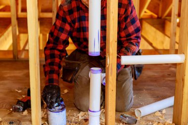 Çimento yapıştırıcısı kullanan tesisatçı plastik borulara PVC boru kullanarak katılıyor. Konut inşaatı için üzerine yapıştırıcı koyuyor.