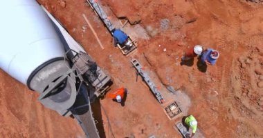 İşçi karıştırıcı kamyon kullanarak hendek inşaatı için beton dökme işlemi hazırlıyor