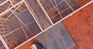 There are beams of wood stick framing in the construction site a new house