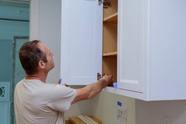 Marangoz yeni evdeki mutfak dolabını tamir ediyor.