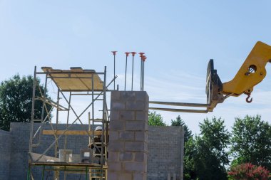 İnşaat alanında paletlere yüklenen beton blokları boşaltmak için kullanılan bir boom forklift var.