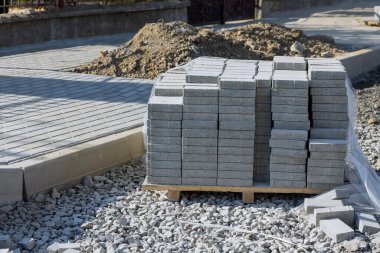 Gri beton tuğla döşeme hazırlığı kaldırım inşaatı peyzaj işçiliği yapıyor.