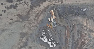 An excavator at work in quarry loading stones into dump truck during mining of gravel stones
