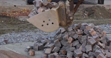 Excavator is pours out rocks stones for laying the road pavement
