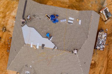 Roofing worker from construction company installed new shingles on roof house