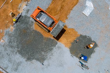 İnşaat alanındaki kovaya çakıl döşemek için bir kazıcı yerleştiriliyor. İnşaat inşaatı için beton dökülmeden önce.