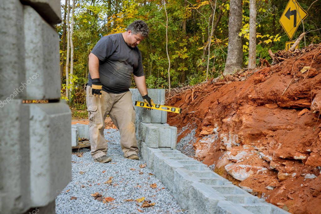 El hombre niveló la pared de bloque de hormigón que se está ...