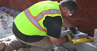 An contractor was installing concrete block after leveling walls on part new retaining wall construction project.