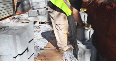 Construction worker was installing concrete block for retaining wall near new home in construction site