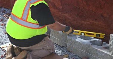 Following leveling of walls on construction site retaining wall contractor installed concrete block.
