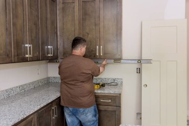 In order to level out installation of brand new kitchen cabinets furniture sets worker hangs level
