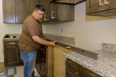 In order to level new kitchen cabinets furniture set during installation, worker hangs level