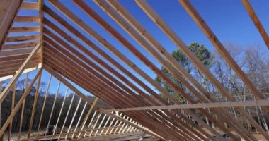 Roofing worker gives details about wooden roof frame at construction site of new house