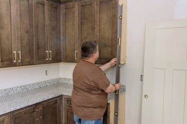 Worker holding level for leveling of new kitchen cabinets before it was installed with its furniture set