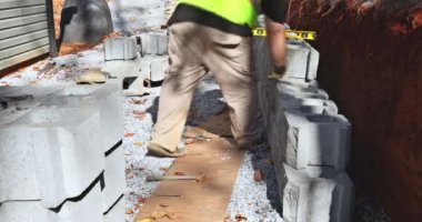 On construction site of construction worker was installing concrete block for retaining wall next to new house