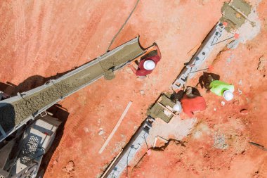 İşçi karıştırıcı kamyon kullanarak hendek inşaatı için beton dökme işlemi hazırlıyor