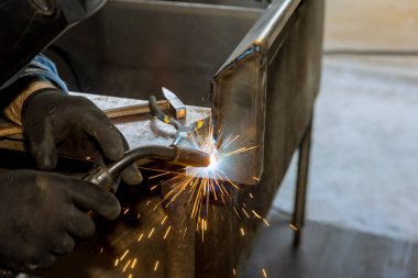 An argon gas shielded arc welding machine is used by worker to weld metal with sparkle on semi automatic welding machine