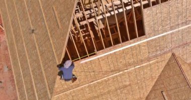 An unfinished house is being reroofed by roofer who is working on installation of plywood roof
