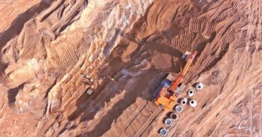 Excavator digging trench for sewer laying connecting underground storm sewer system pipes at construction site