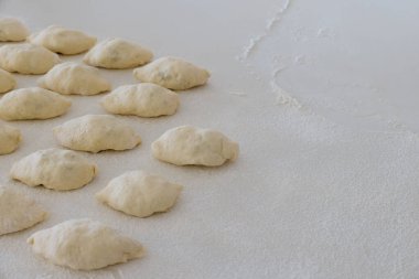 Homemade buns with potatoes made from yeast dough on white countertop as they are being made