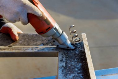 Worker is using electric scissors to cut metal using double shear gauge