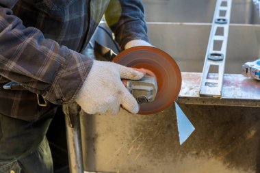 Worker uses grinder to cut metal with sparks while grinding iron with grinder