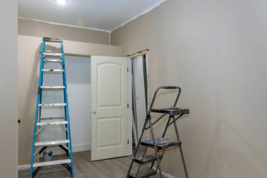 Empty room has painted wall with painting equipment and stepladder