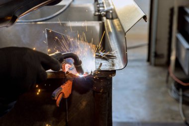 Worker working welding metal with sparkle using welding machine semi automatic argon gas shielded welding