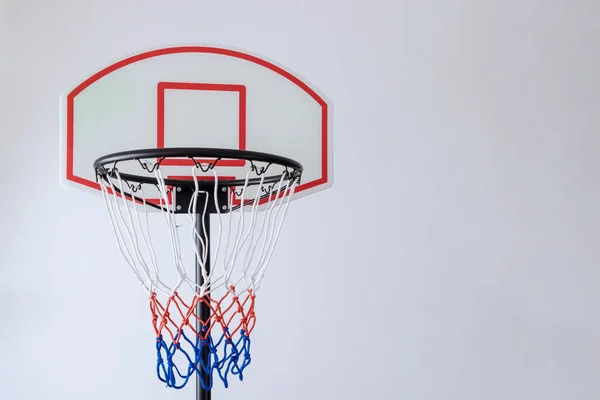 On white background basketball basket hoop is positioned in rim with net attached
