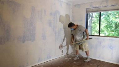 Sanding is being done by worker using sand trowel while renovating house in room where drywall mud being applied