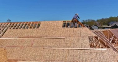 Work being done by carpenter roofer on putting plywood over an unfinished houses roof